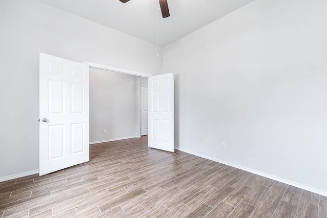 unfurnished bedroom featuring ceiling fan, light wood-type flooring, and a high ceiling