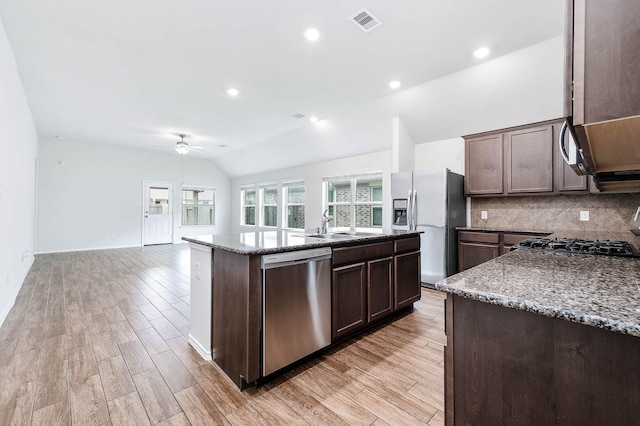 kitchen with stainless steel appliances, vaulted ceiling, ceiling fan, light hardwood / wood-style floors, and an island with sink