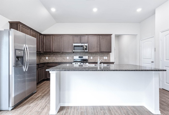 kitchen featuring a center island with sink, sink, vaulted ceiling, light hardwood / wood-style flooring, and stainless steel appliances