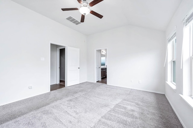 unfurnished bedroom with dark carpet, ensuite bath, vaulted ceiling, and ceiling fan