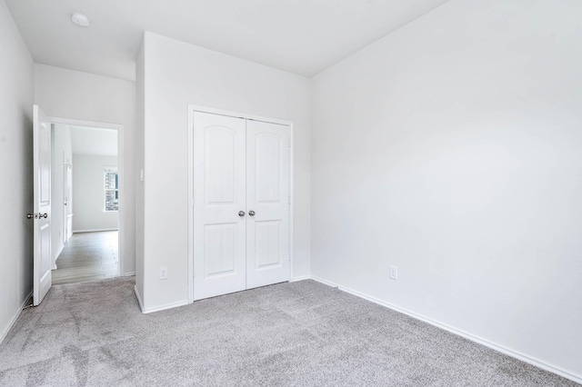 unfurnished bedroom with light colored carpet and a closet