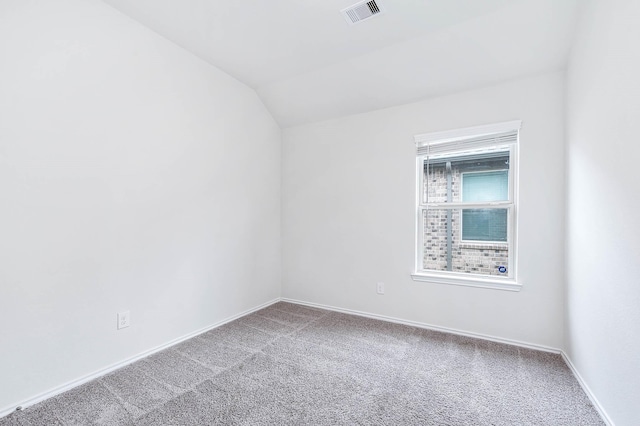 spare room with carpet flooring and vaulted ceiling