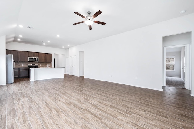 unfurnished living room with ceiling fan, wood-type flooring, and vaulted ceiling