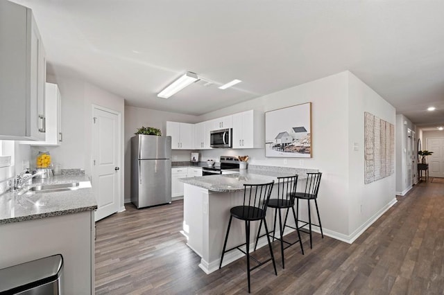 kitchen featuring kitchen peninsula, white cabinets, dark hardwood / wood-style floors, and appliances with stainless steel finishes