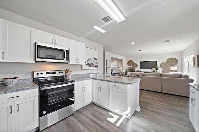 kitchen with hardwood / wood-style flooring, white cabinetry, and appliances with stainless steel finishes