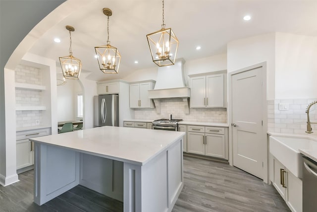 kitchen with custom exhaust hood, backsplash, dark wood-type flooring, decorative light fixtures, and stainless steel appliances