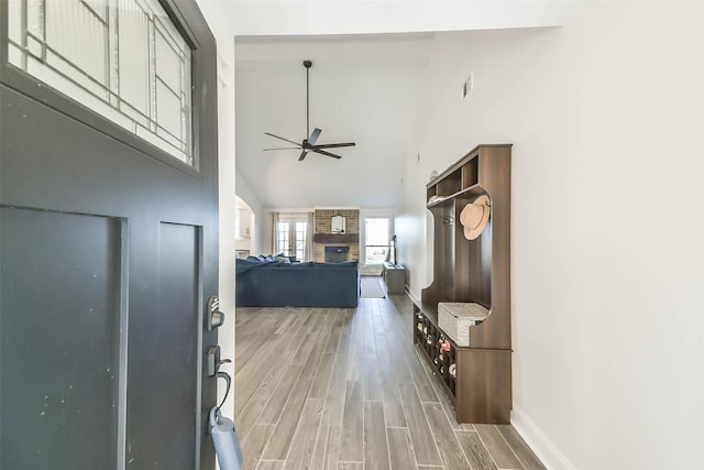 entryway with ceiling fan, a towering ceiling, and wood-type flooring