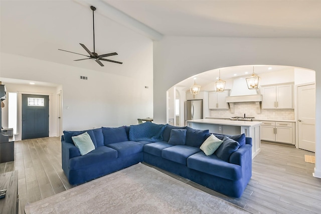 living room featuring light wood-type flooring, lofted ceiling with beams, and ceiling fan