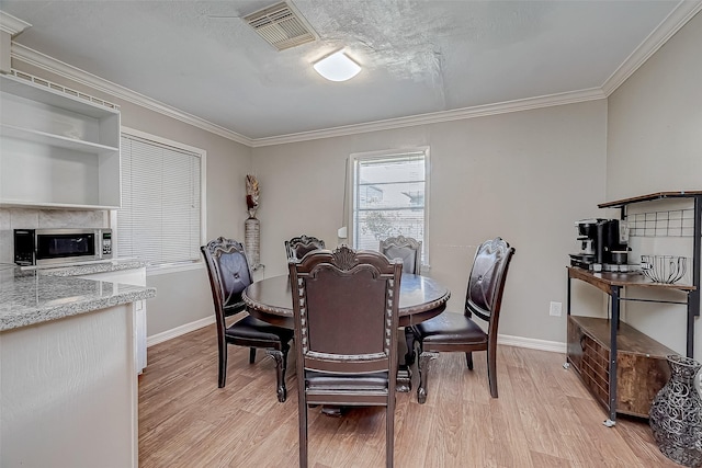 dining space featuring crown molding, a textured ceiling, and light hardwood / wood-style flooring