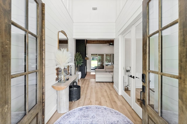 hallway with french doors, a high ceiling, and light wood-type flooring