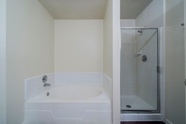 bathroom with plus walk in shower and a textured ceiling