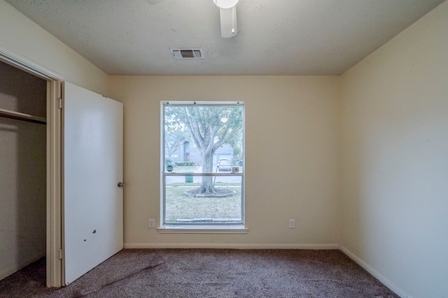 unfurnished bedroom featuring carpet flooring, ceiling fan, a textured ceiling, and a closet