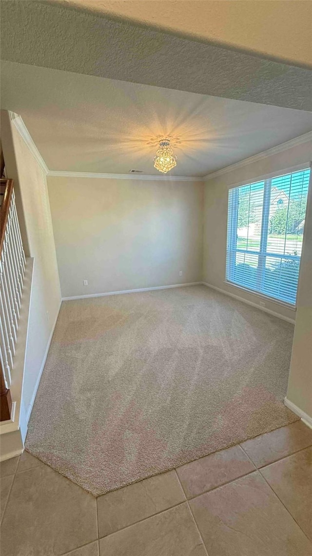 carpeted empty room with ornamental molding, a textured ceiling, and an inviting chandelier