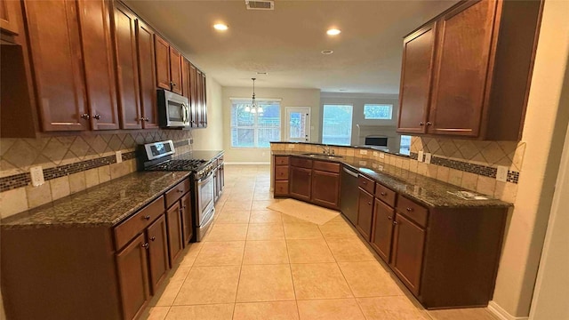 kitchen with kitchen peninsula, decorative light fixtures, stainless steel appliances, and decorative backsplash