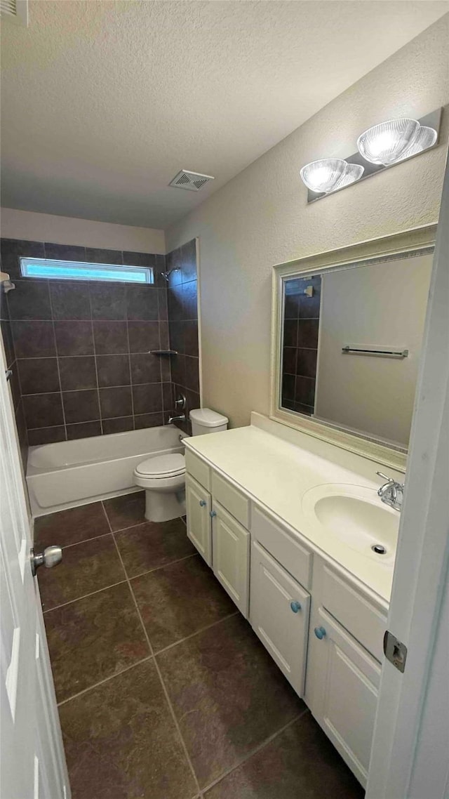 full bathroom with vanity, tiled shower / bath, tile patterned flooring, toilet, and a textured ceiling