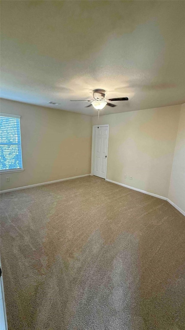 spare room featuring ceiling fan and carpet floors