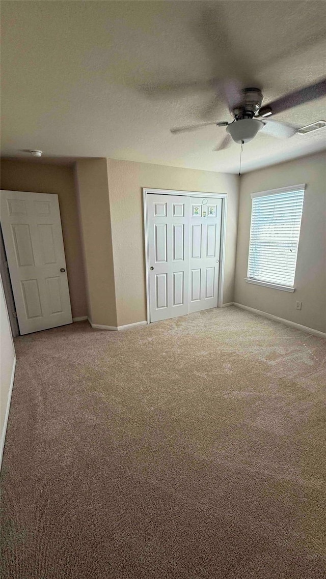 unfurnished bedroom with carpet flooring, ceiling fan, and a textured ceiling