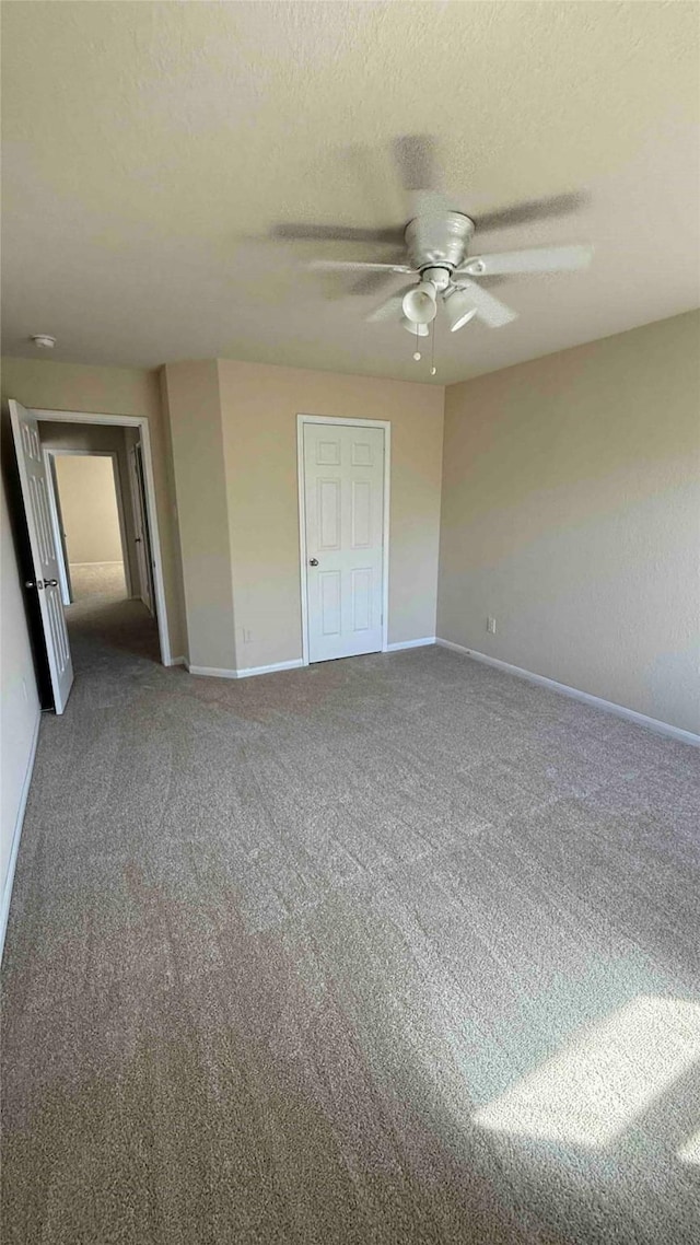 unfurnished bedroom featuring a textured ceiling, carpet floors, and ceiling fan