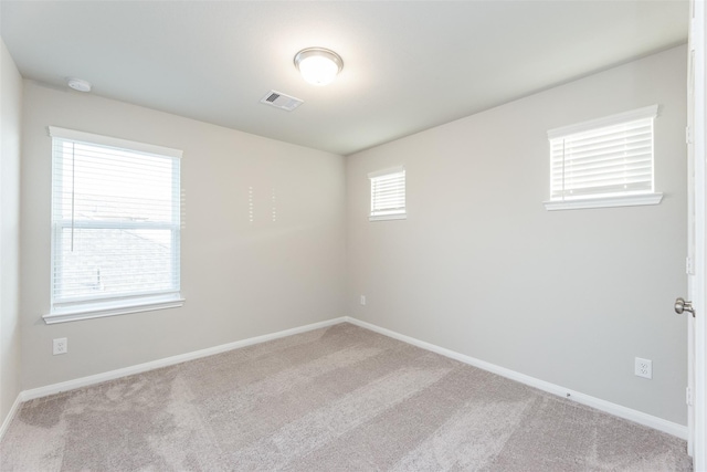 spare room featuring a healthy amount of sunlight and light colored carpet