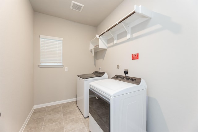 clothes washing area featuring washer and clothes dryer and light tile patterned floors