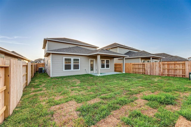 rear view of property with a yard, central AC, and a patio area