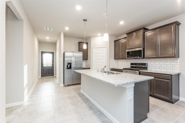 kitchen featuring pendant lighting, sink, an island with sink, appliances with stainless steel finishes, and tasteful backsplash