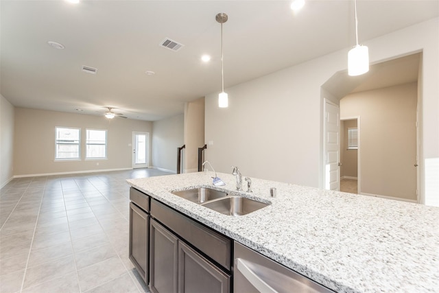 kitchen featuring light stone countertops, ceiling fan, sink, pendant lighting, and light tile patterned floors