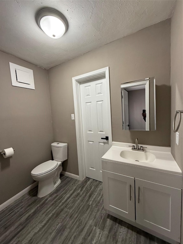 bathroom with hardwood / wood-style floors, vanity, a textured ceiling, and toilet