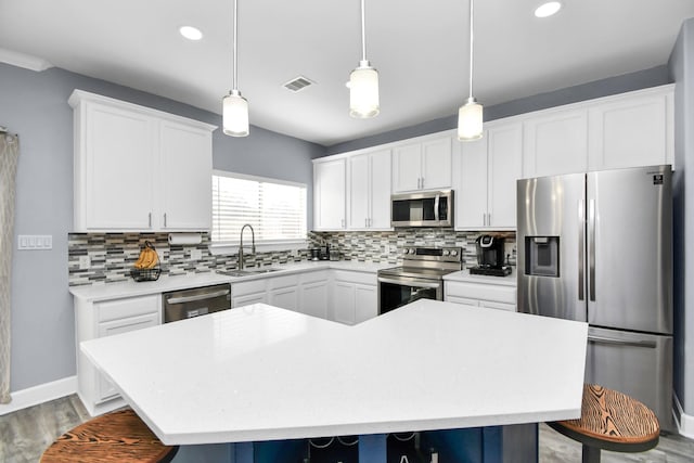 kitchen with pendant lighting, a center island, backsplash, sink, and stainless steel appliances