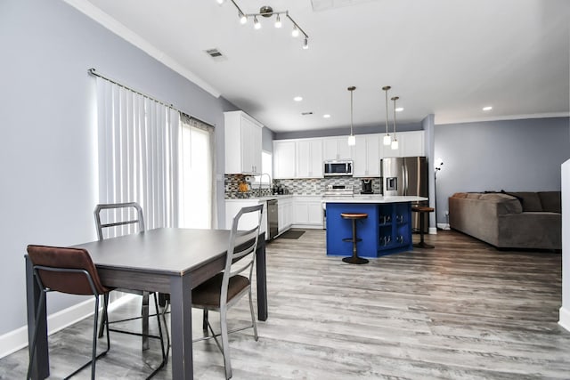 dining space with sink, ornamental molding, and light wood-type flooring