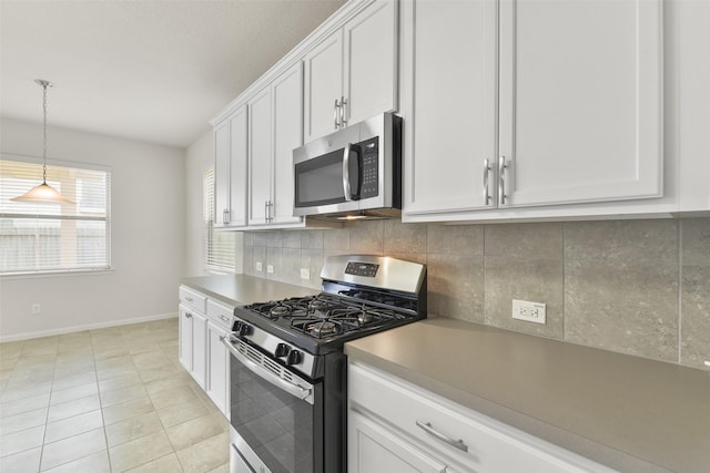 kitchen with light tile patterned floors, appliances with stainless steel finishes, backsplash, hanging light fixtures, and white cabinets