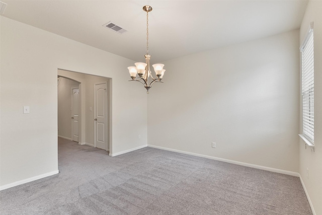 carpeted spare room with a chandelier