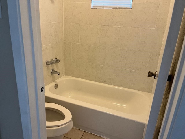 bathroom featuring tile patterned flooring, toilet, and tiled shower / bath