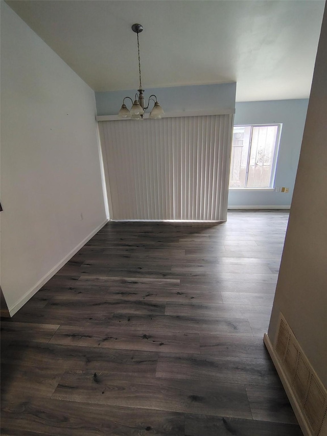 unfurnished dining area featuring a chandelier and dark hardwood / wood-style flooring