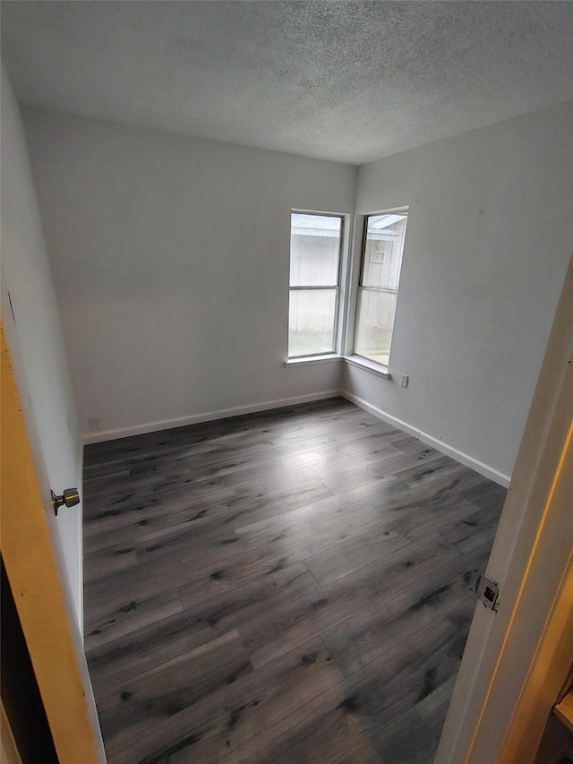 spare room with dark wood-type flooring and a textured ceiling