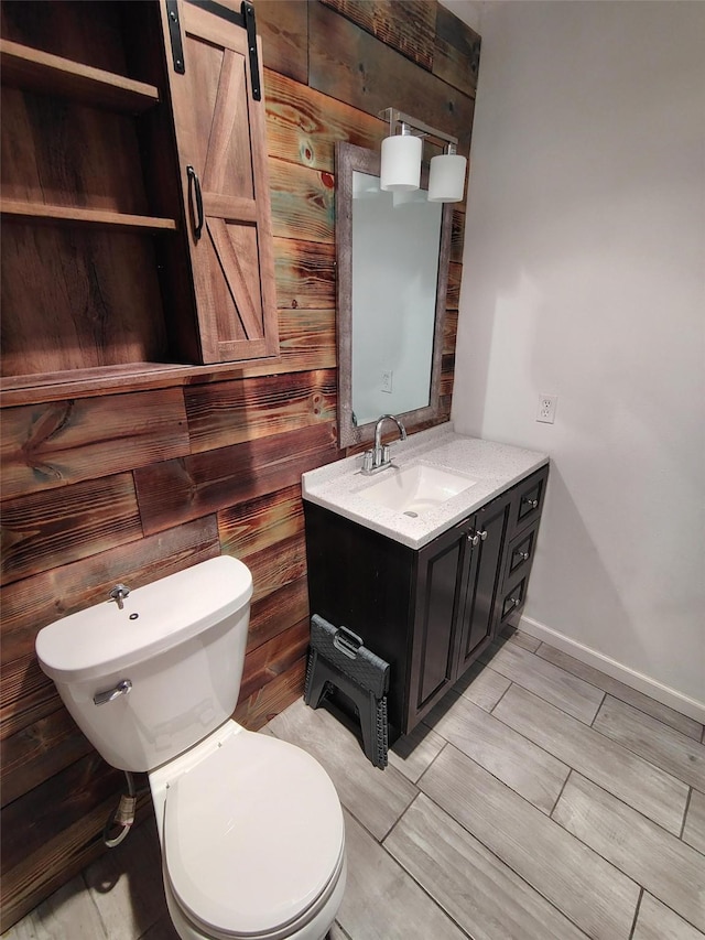 bathroom featuring vanity, wood walls, and toilet