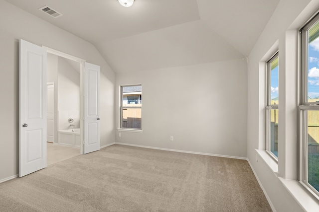 unfurnished bedroom with light carpet, multiple windows, and lofted ceiling