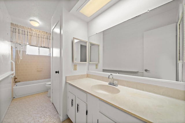 full bathroom with tiled shower / bath, vanity, a textured ceiling, and toilet