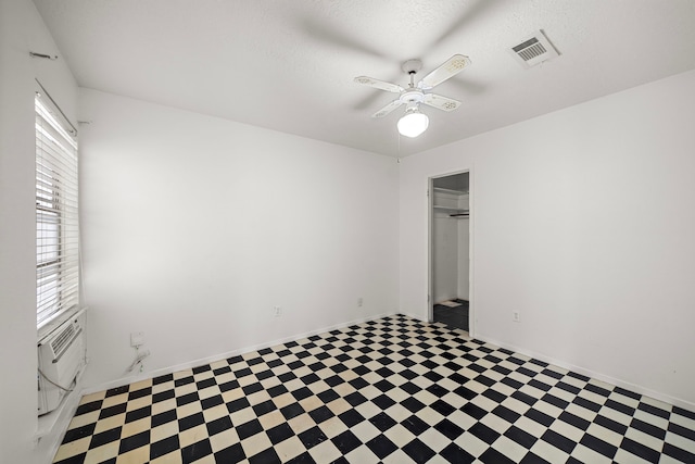 empty room featuring ceiling fan, plenty of natural light, cooling unit, and a textured ceiling