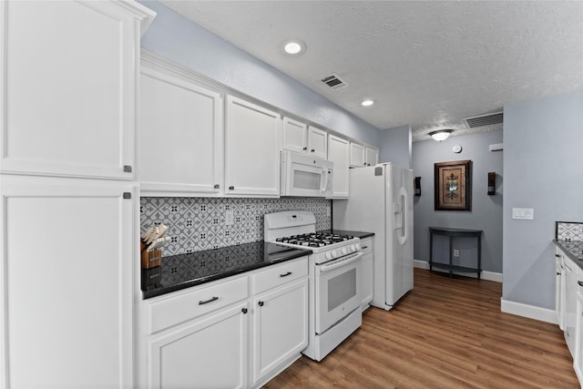 kitchen with white appliances, hardwood / wood-style flooring, a textured ceiling, tasteful backsplash, and white cabinetry