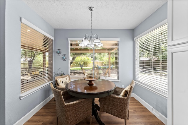 dining space with a textured ceiling, dark hardwood / wood-style floors, and an inviting chandelier