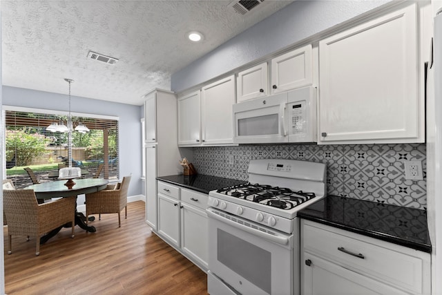 kitchen featuring white appliances, hanging light fixtures, tasteful backsplash, light hardwood / wood-style floors, and white cabinetry