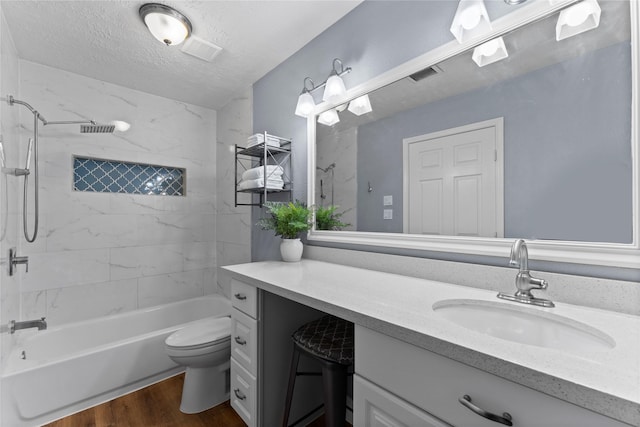 full bathroom with vanity, tiled shower / bath combo, toilet, a textured ceiling, and wood-type flooring