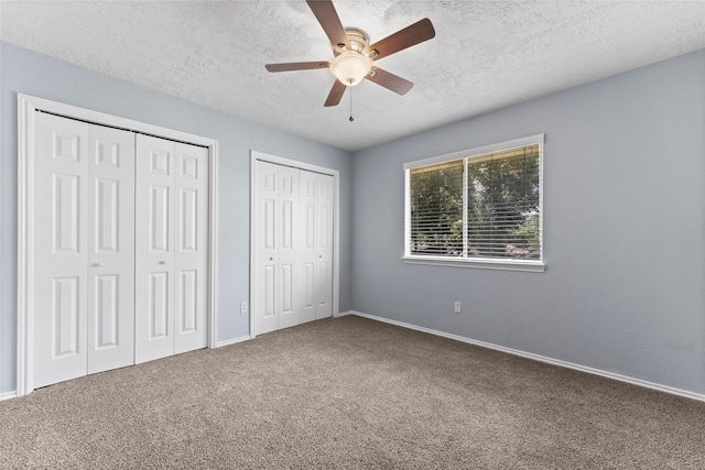 unfurnished bedroom with ceiling fan, carpet, and two closets