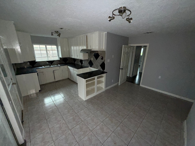 kitchen with sink, a textured ceiling, tasteful backsplash, white cabinetry, and a chandelier