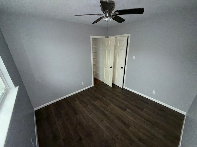 unfurnished bedroom with ceiling fan, a closet, and dark hardwood / wood-style floors