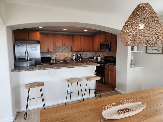 22901 Buena St, Galveston, TX 77554 - kitchen featuring sink, a kitchen bar, decorative backsplash, appliances with stainless steel finishes, and hardwood / wood-style flooring