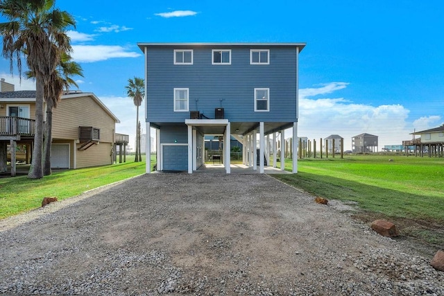 22901 Buena St, Galveston, TX 77554 - back of house with a carport, a garage, and a lawn