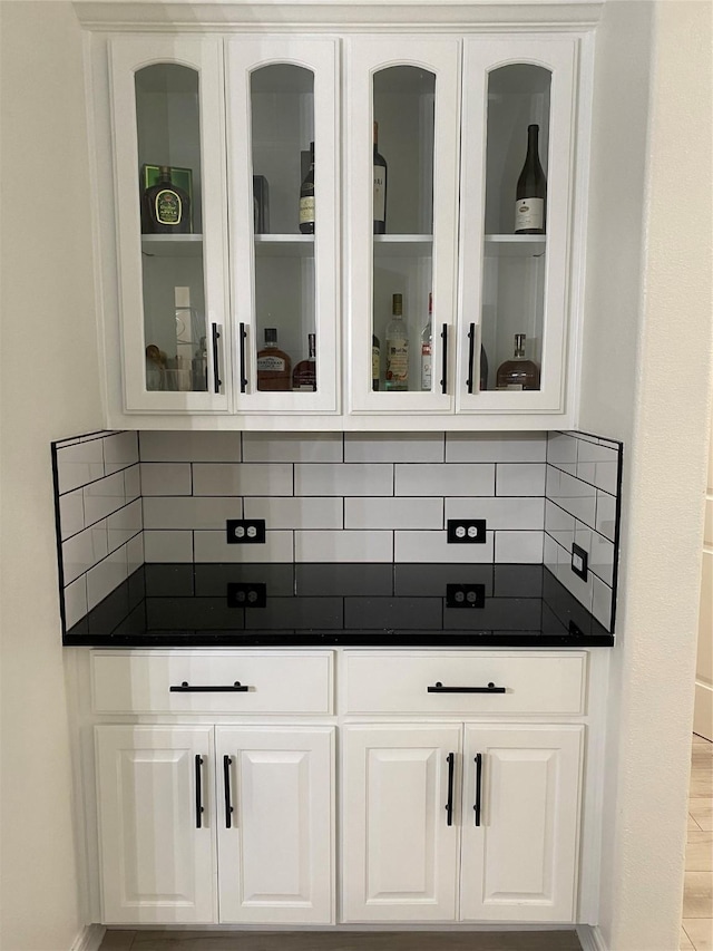 bar featuring tasteful backsplash and white cabinetry