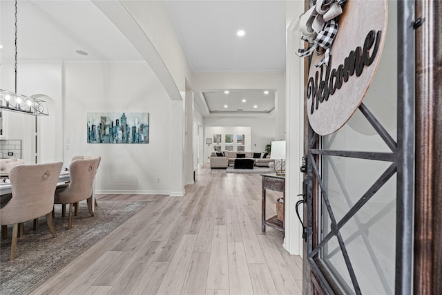 foyer featuring a notable chandelier, ornamental molding, and light wood-type flooring